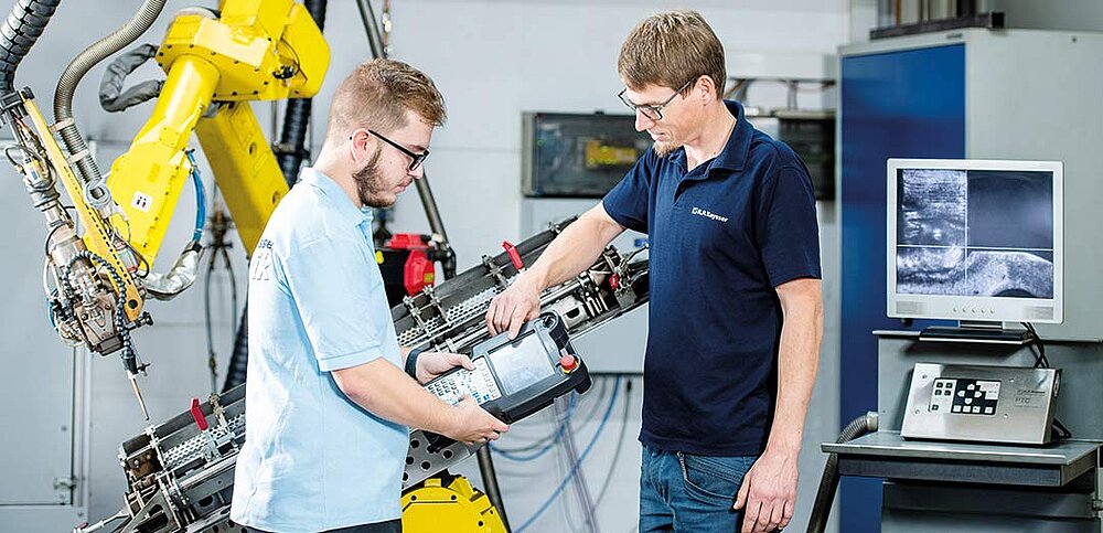 Ausbilder erklärt Azubi Roboteranlage