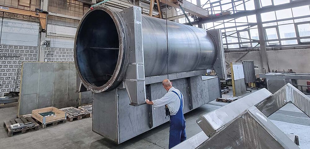 Mitarbeiter bedient Kran mit sehr großem Bauteil