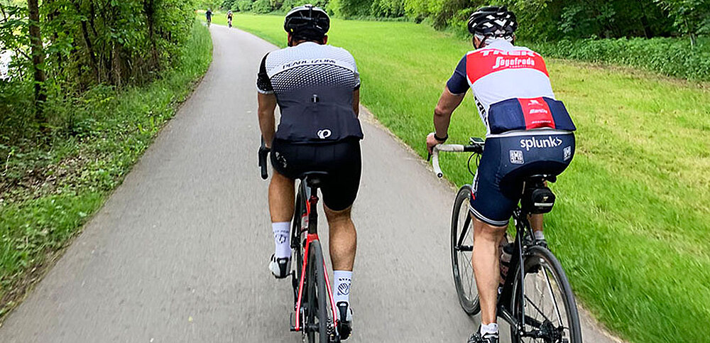 Zwei Radfahrer fahren entlang einer grünen Wiese