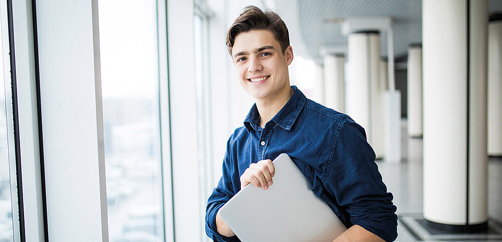 Student mit Laptop im Arm
