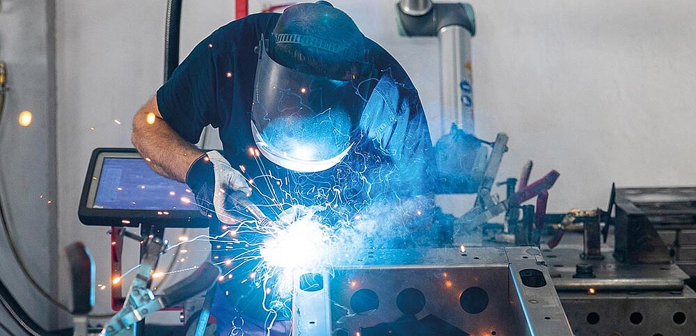 Schweißer arbeitet an Kundenauftrag und wirft Schweißfunken